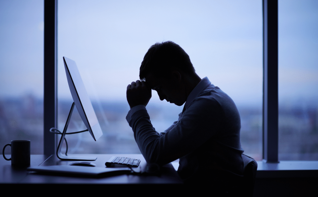 A man in front of his computer looking tired. Workplace Fatigue. Safety Software to manage NEW Psychosocial regulations.